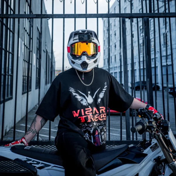 Model wearing the Dove Tee while sitting on a dirt bike at a gate